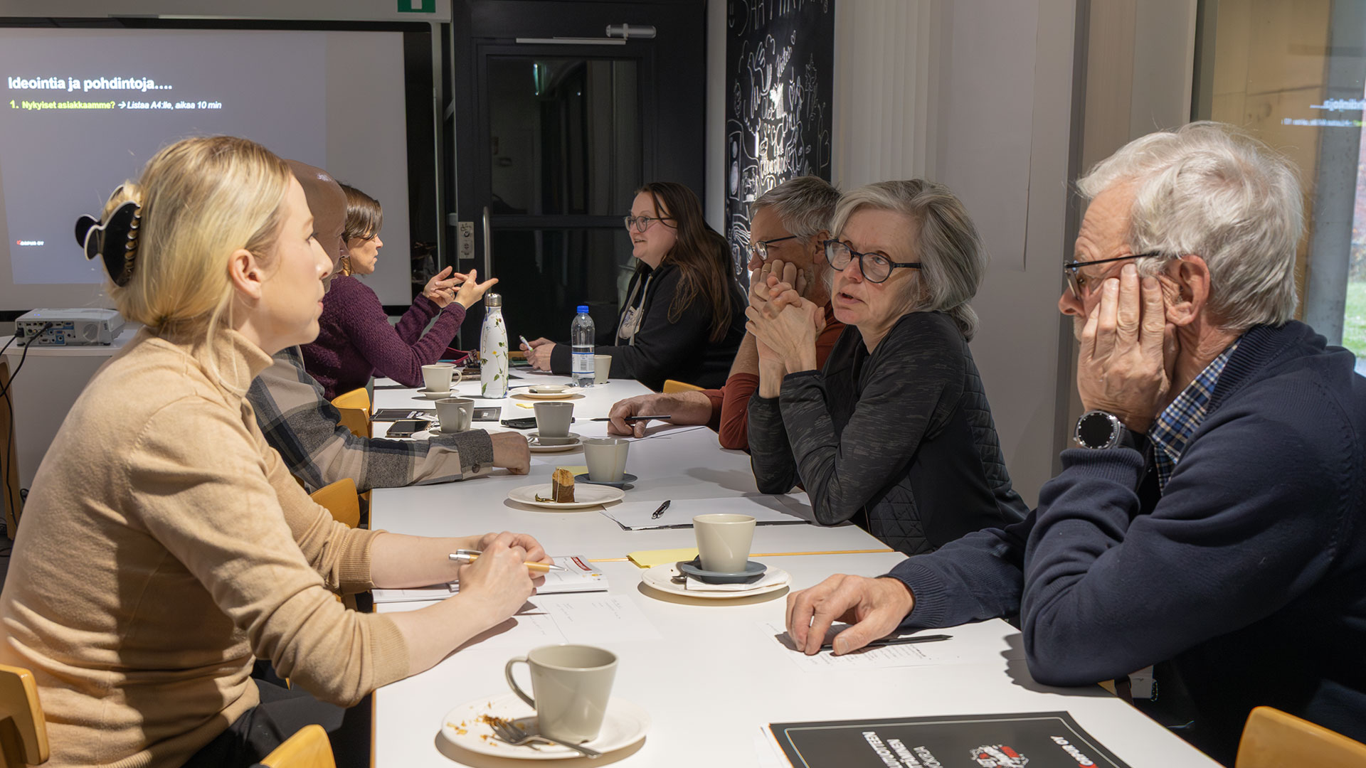 Ihmisiä istuu pöydän ääressä keskustelemassa.