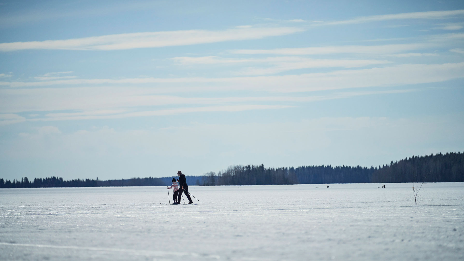 Aikuinen ja lapsi hiihtämässä jäällä.