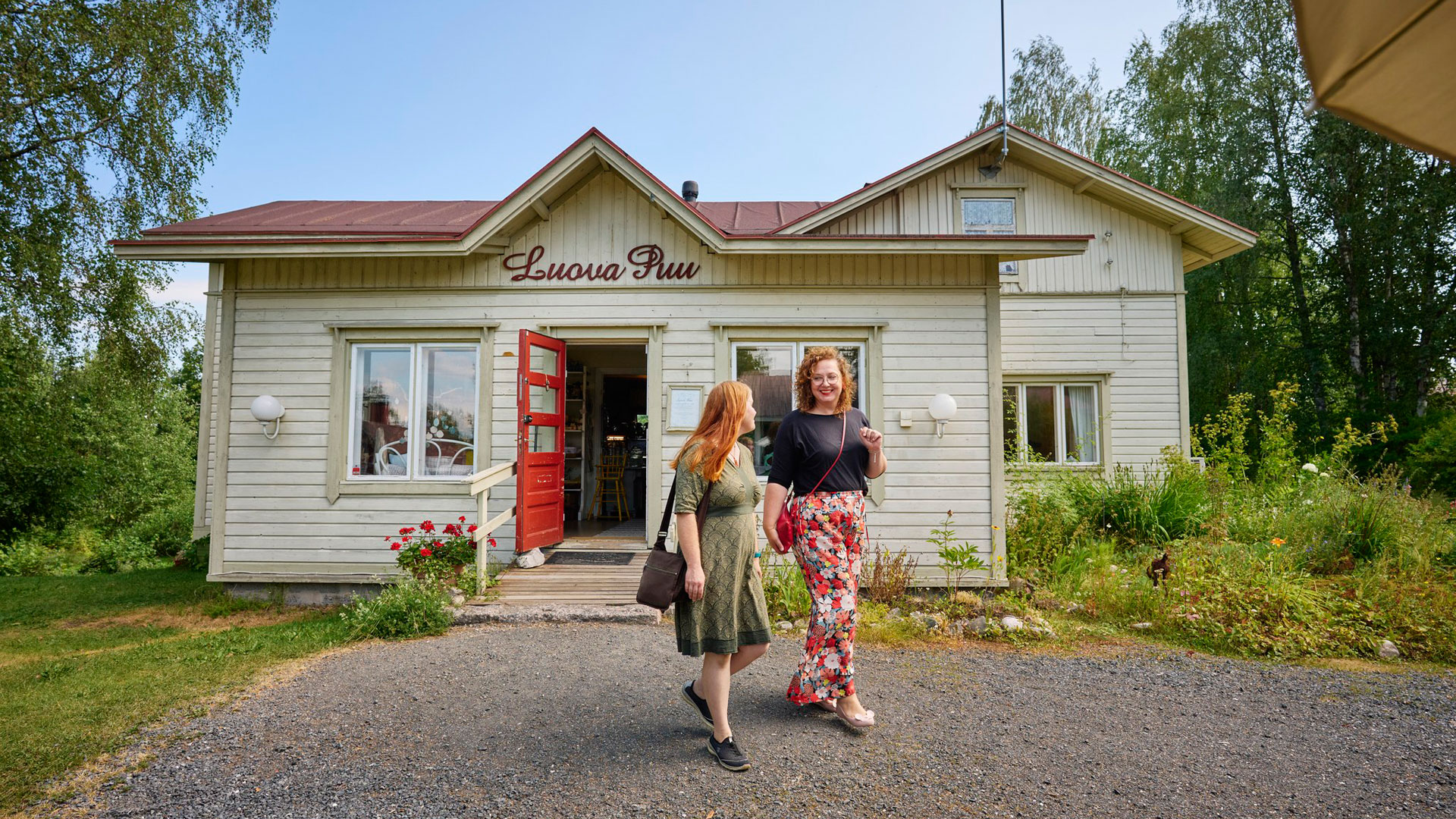 Kaksi naista kävelee pihamaalla Luovan Puun päärakennuksen edessä.