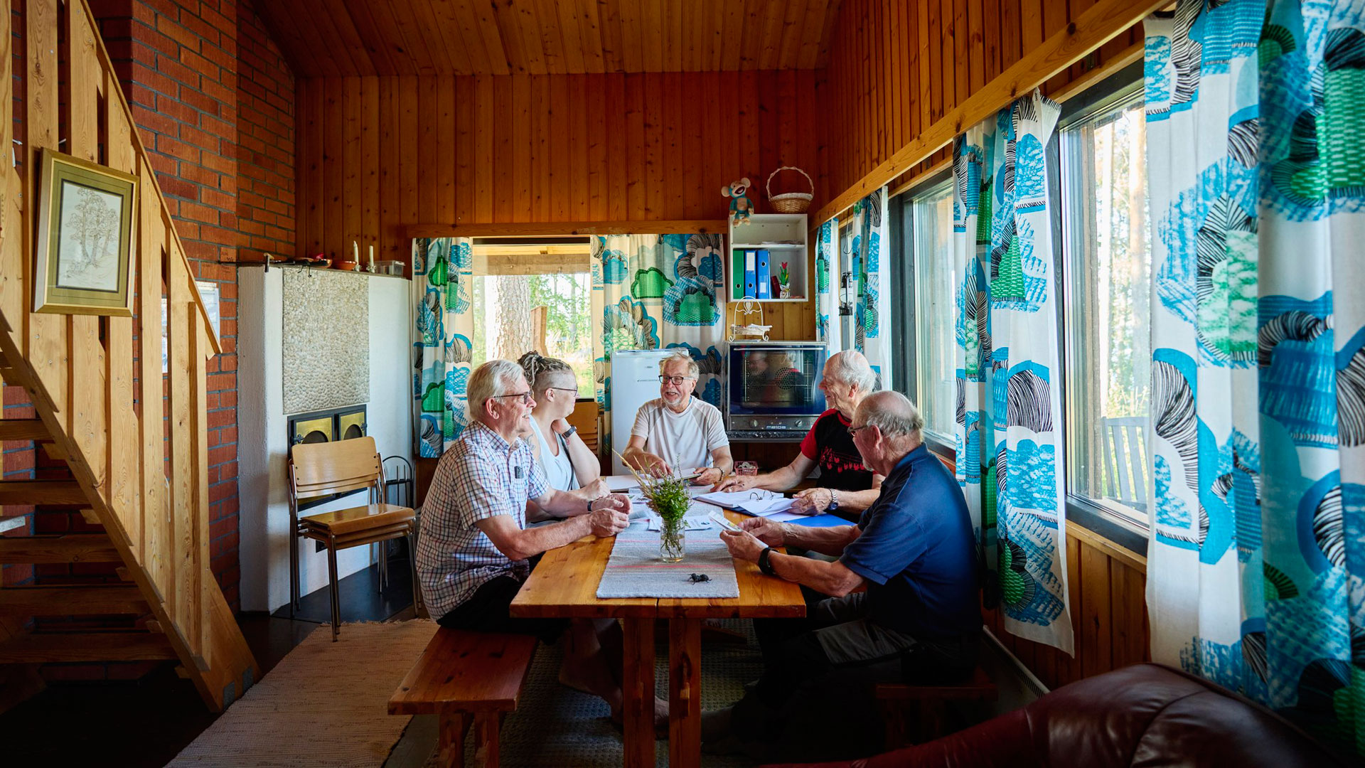 Pöydän ympärillä istuu viisi henkilöä, joilla edessään papereita.