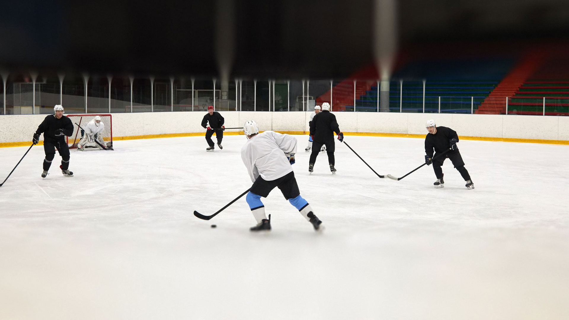 Viisi luistelijaa pelaamassa jääkiekkoa.